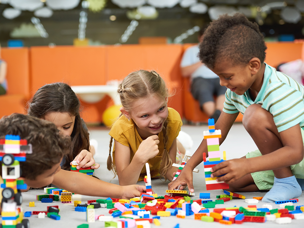 Group of four children playing with colorful blocks