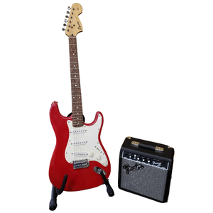 red electric guitar next to black amp