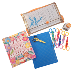 scrapbooking items including scissors, paper, and cutting mat