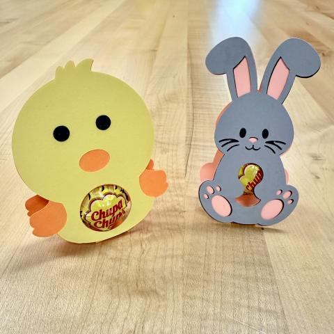 Yellow paper chick with hole for candy sucker in tummy, gray rabbit with hole for candy sucker in tummy