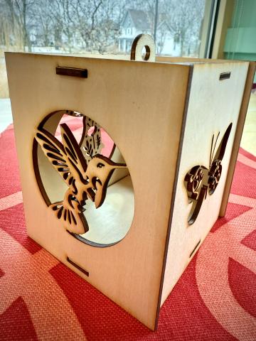 box with cut out of butterfly on right side and a cut out of a hummingbird on the left side