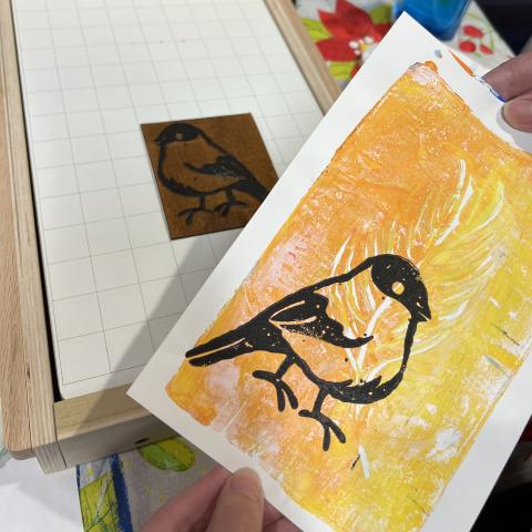wood carving of bird, yellow and orange gelli plate print with black bird on it 