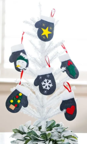 White Holiday Tree with small mittens with snowflakes, stars, and hearts on the mittens hanging on the tree.