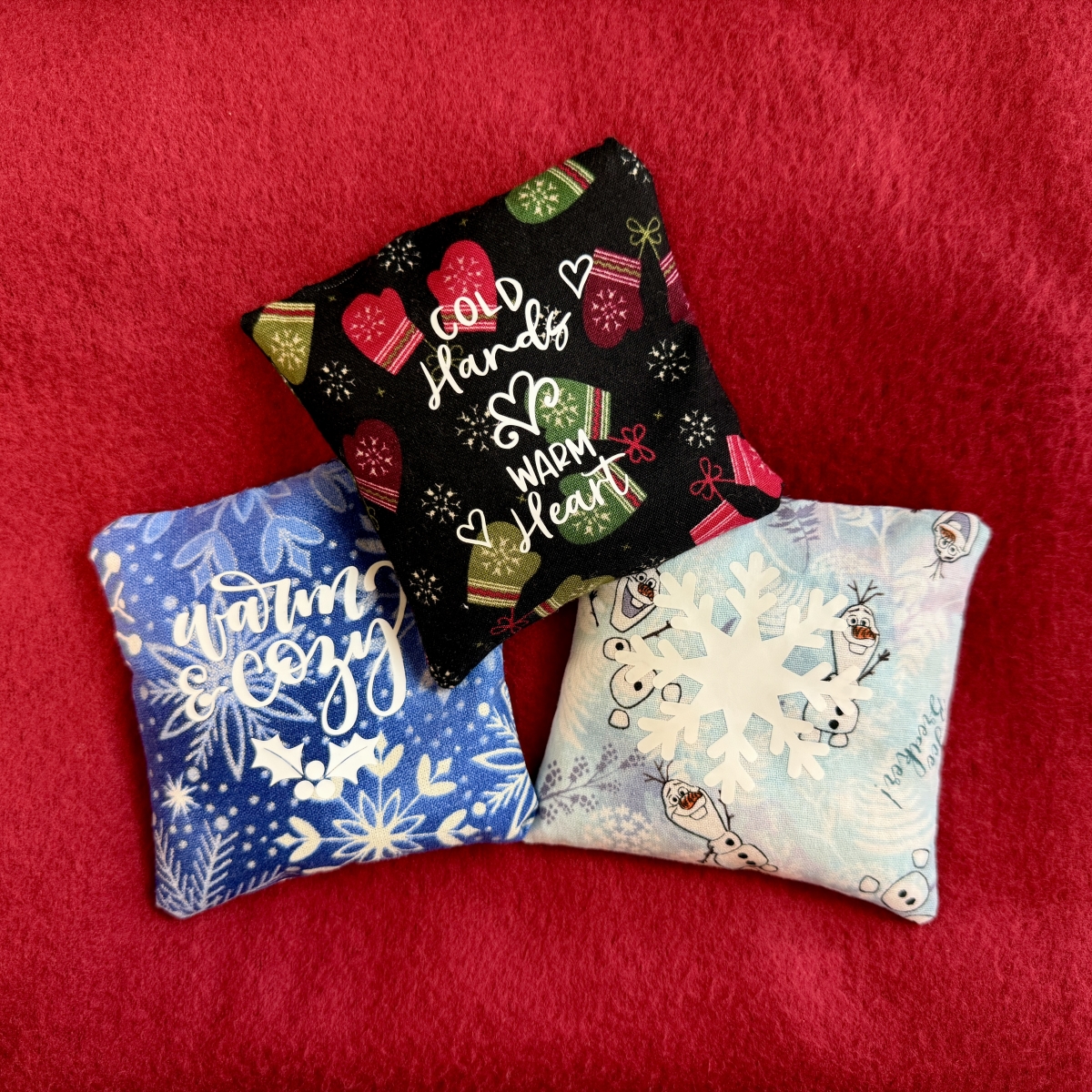 Red background with three small square handwarmers made out of different material.